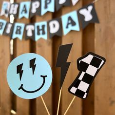 a happy birthday cake topper on a stick in front of a wooden fence with black and white checkered flags