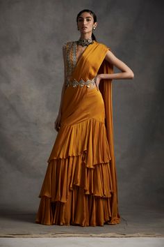 A vibrant pre-stitched layered saree with an embroidered cutwork belt. The saree is paired with a pearl, sequins, tilla & mirror work hand embroidered blouse. The sleeves have pearl & sikka... Luxury Traditional Wedding Dress With Drape, Luxury Pre-draped Saree With Mirror Work For Diwali, Luxury Bollywood Pre-draped Yellow Saree, Luxury Yellow Bollywood Pre-draped Saree, Luxury Bollywood Yellow Pre-draped Saree, Luxury Traditional Saree With Latkans, Drape Lehenga, Bhumika Sharma, Pleated Saree