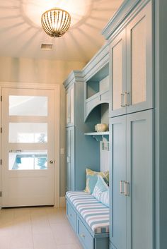 a room with blue cabinets and a bench in the middle, next to a white door