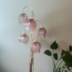 a pink glass flower is sitting on a stand next to a potted green plant