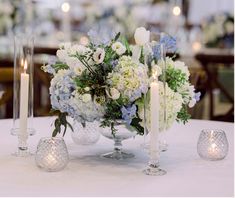 a centerpiece with flowers and candles on a table