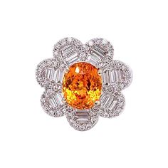 A special ring designed as a flower centered by a vivid orange mandarin garnet. It has a clean and clear crystal and weights 3.75 carats as a oval shape. It is accented by 1.08 carats of round and baguette cut diamonds all set in 18k white gold. A fun and quality ring that you will not want to take off. Ring Size 5.75 Elegant Multi-stone Orange Rings, Elegant Orange Multi-stone Rings, Luxury Orange Oval Jewelry, Orange Oval Center Stone Jewelry, Oval Orange Jewelry With Center Stone, Orange Oval Jewelry With Center Stone, Fine Jewelry Orange Oval, Fine Jewelry Orange Oval Jewelry, Elegant Orange Oval Rings