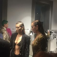 two women standing next to each other in front of clothes on mannequins