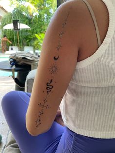 the back of a woman's arm with stars and moon tattoos on it, in front of a pool