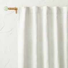 a white curtain hanging on the side of a wall with a green light bulb attached to it