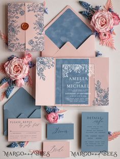 the wedding stationery is laid out with pink flowers and blue envelopes on top