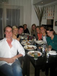 a group of people sitting at a table with plates of food and drinks in front of them