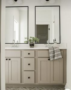 a bathroom with double sinks and mirrors above it's countertop, along with two planters on either side of the sink