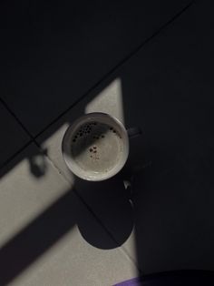 a coffee cup sitting on top of a white floor next to a purple table cloth