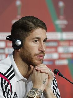 a man with headphones on his ears sitting in front of a microphone at a press conference