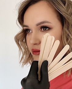 a woman with black gloves holding wooden sticks in front of her face