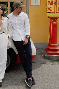 a man and woman standing next to a car