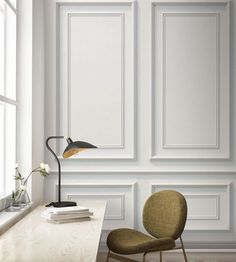 an empty room with a chair, lamp and books on the table in front of it