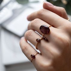 Tiny Oval Garnet ring featuring a shimmering gold-filled band that gracefully wraps around your finger. What sets it apart is its crystal: a captivating, deep-red natural crushed Garnet stones encased in a glass-like resin, effortlessly catching the eye without overwhelming the senses. The Garnet’s rich hue, evocative of fallen leaves and autumn sunsets, brings an element of seasonal warmth to any ensemble. The fine gold-filled chain is both dainty and durable, the perfect balance of delicacy and strength that promises long-lasting wear. Perfect for stacking. Metal: 14k gold filled or Sterling Silver. Style: Oval 6x4mm crystal on a 1mm thick band. Size: Available in many sizes ready to ship. If you would like your ring made in a custom size feel free to reach out. Rhodonite Ring, Fallen Leaves, Oval Ring, Garnet Ring, Oval Rings, Garnet Stone, Silver Style, Garnet Rings, Bracelet Collection