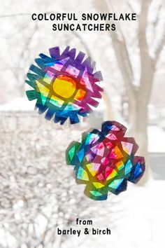 two colorful snowflake suncathers hanging from a tree in the snow with text overlay that reads, colorful snowflake sun catchers from barley & birch