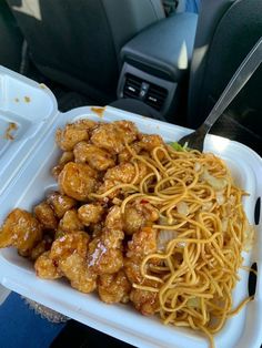 a plastic container filled with noodles and meat on top of a car dash board seat