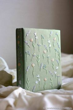 a book with flowers painted on it sitting on a bed