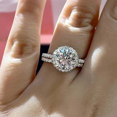 a woman's hand with a diamond ring on top of her finger and an engagement band