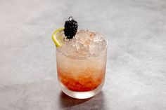 a drink with ice and blackberries garnishes on the rim, sitting on a table