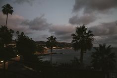 palm trees and the ocean at dusk with clouds in the sky over them, as seen from a balcony