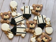 decorated cookies with teddy bears in black and white outfits on a wooden table, ready to be eaten