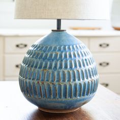 a blue vase sitting on top of a wooden table next to a lampshade