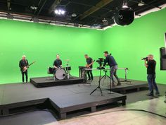 a group of people standing on top of a stage in front of a green screen