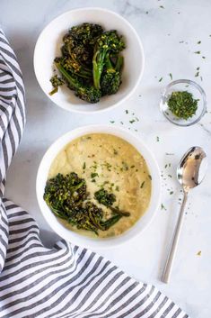 two white bowls filled with broccoli on top of a marble counter next to silverware