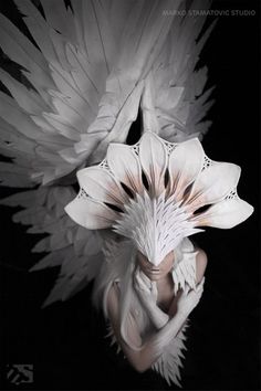 a woman with white feathers on her head and wings around her face, in black and white