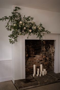 a fireplace with candles and flowers on it