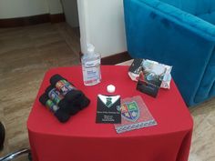 a red table topped with books next to a blue chair and bottle of water on top of it