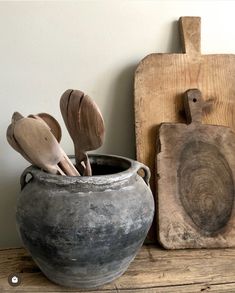 some wooden spoons are in a gray vase