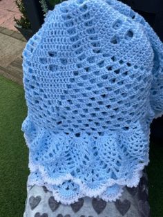 a crocheted blue blanket sitting on top of a green lawn covered in hearts