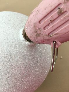 a pink mixer is being used to mix up some white and pink stuff on a table