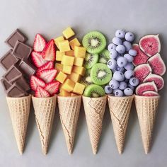 four ice cream cones filled with different types of fruits and chocolates on top of each other