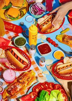 a table full of hot dogs, hamburgers and other condiments on it