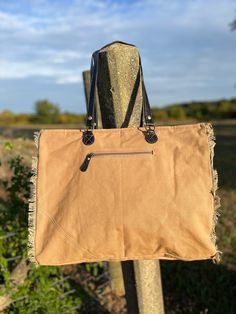 This great bag features plenty of space to carry a variety of items, from clothes to groceries! A dimensional front, with two-tone canvas, a sewn leather star accent, extra flapped pocket with fanciful worded overprinting, and frayed-edge treatments make for a delightfully textured look. An additional zippered pocket on front, zipper-close top, woven canvas back with zippered pocket, and durable black leather carrying shoulder straps finish everything out. Materials: Canvas & LeatherItem Width: 19"Item Depth: 8"Item Height: 16" Handle: 12" Canvas Hobo Bag With Removable Pouch, Brown Cotton Shoulder Bag With Leather Trim, Cotton Bag With Leather Trim For On-the-go, On-the-go Cotton Bags With Leather Trim, Cotton Satchel Bag With Leather Trim, Cotton Shoulder Bag With Leather Trim Satchel, Brown Cotton Canvas Bag For Errands, Cotton Shoulder Bag With Removable Pouch For Errands, Light My Fire