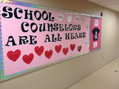 a pink bulletin board with hearts and words on it in an empty school hallway area