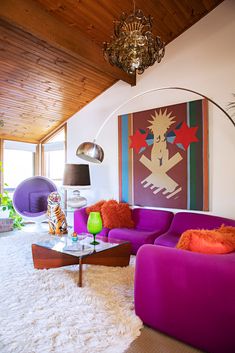 a living room filled with furniture and a chandelier hanging from the ceiling over a white rug