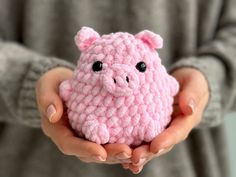 a person holding a small pink crocheted pig in their hands with both hands