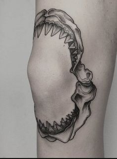 a black and white photo of a shark's teeth tattoo on the right thigh