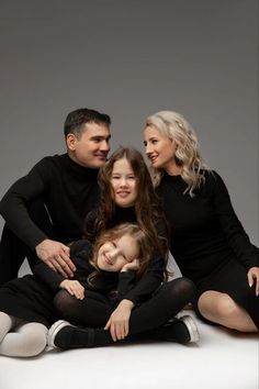 a family sitting on the floor together posing for a photo in their black outfits and white socks