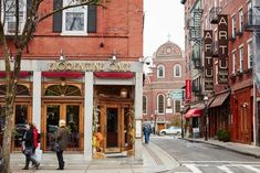 people are walking down the street in front of an artful store with red awnings