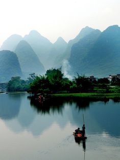 a small boat floating on top of a lake surrounded by mountains