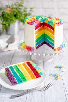 a slice of rainbow cake sitting on top of a white plate next to a fork