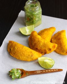 some food is laying out on a piece of paper with a spoon and lime wedges next to it