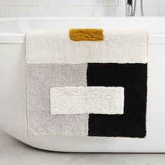 a white bath tub sitting next to a black and white rug on top of it