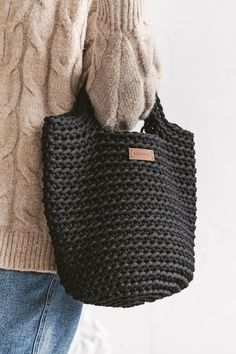 a woman carrying a black crochet bag