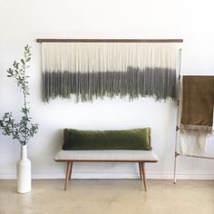 a white bench sitting in front of a wall hanging