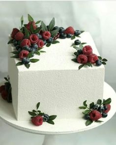 a white cake with berries and leaves on it